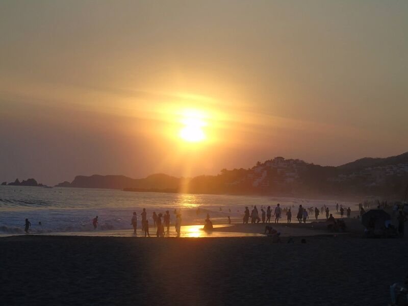 Atardecer en la playa con siluetas en la orilla