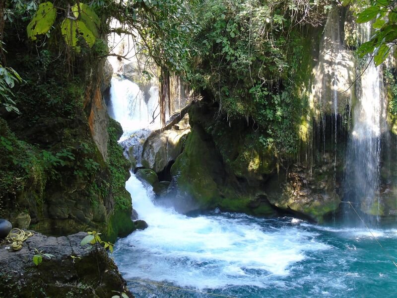 Poza turquesa con velo de cascada y roca con musgo